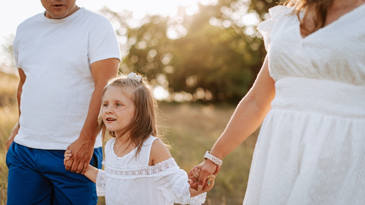 A man and a woman holding hands with a little girl